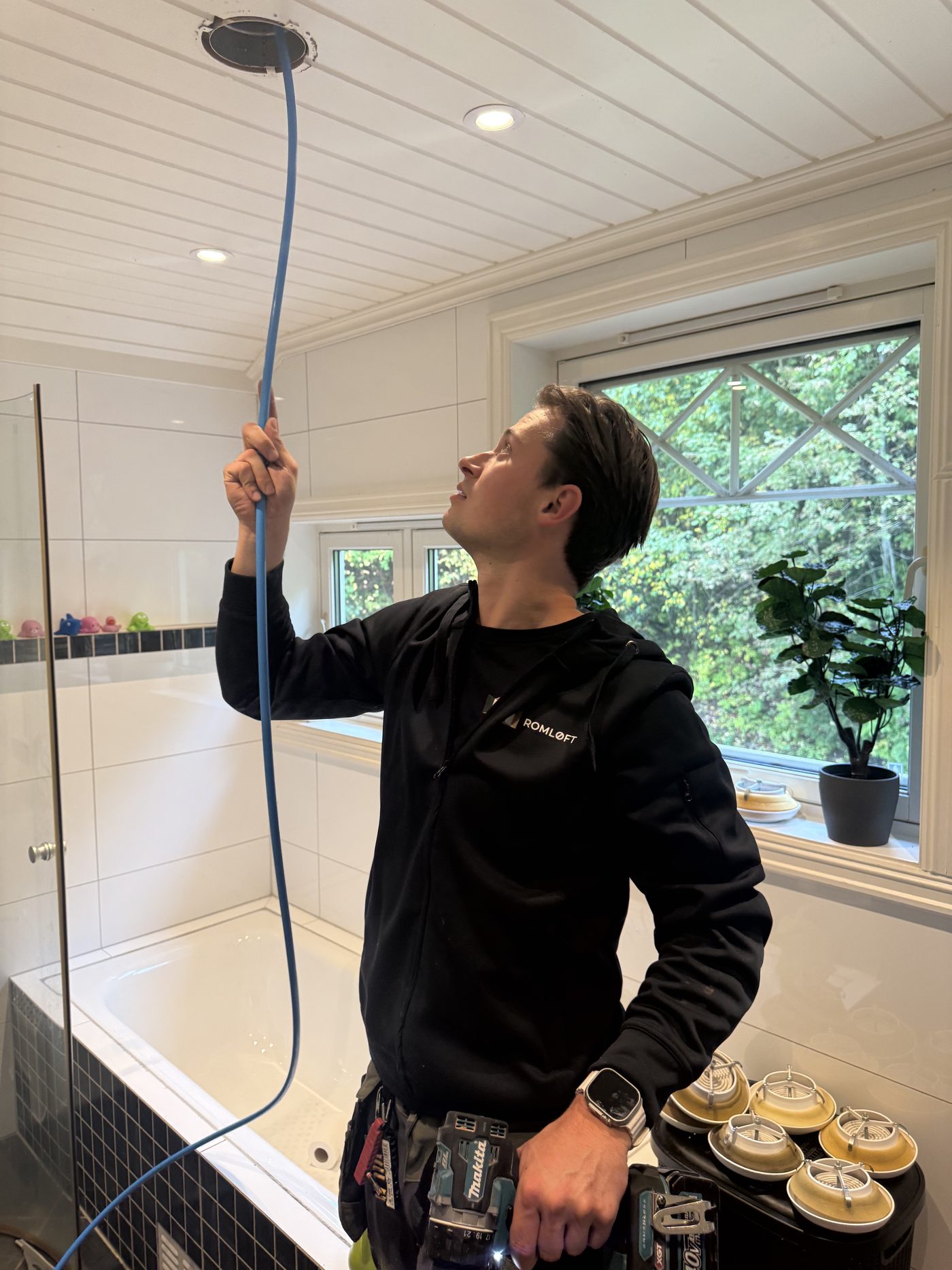 Tekniker fra Romløft renser ventilasjon på et bad